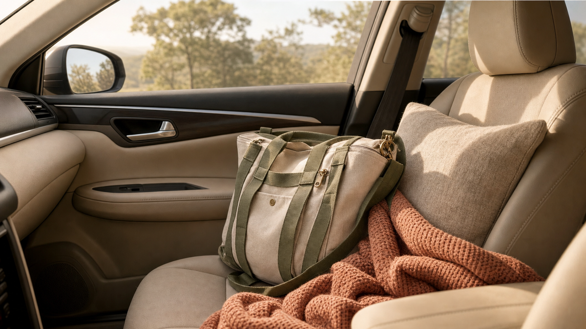 Serene car interior in soft morning light with a travel canvas bag, terracotta knit throw, and warm sand cushion on the seat
